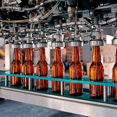 Glass bottles move through a beverage manufacturing plant. Monitoring water hardness is important to managing product quality.